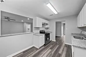 a kitchen with granite countertop a sink stainless steel appliances and white cabinets