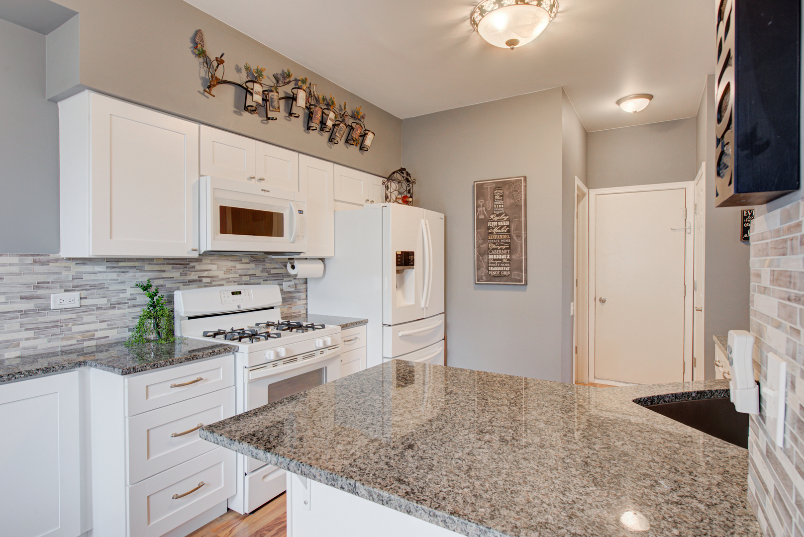 1201 Delta Drive Elgin, IL 60123 - Photo 15 of 42 a kitchen with stainless steel appliances kitchen island granite countertop a refrigerator a stove a microwave oven with white cabinets and wooden floor