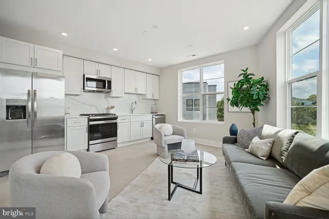 a living room with furniture a fireplace a flat screen tv and windows