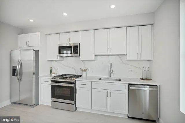 a kitchen with white cabinets and stainless steel appliances
