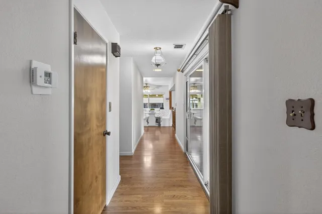 a dining room with wooden floor a chandelier fan a wooden table and chairs