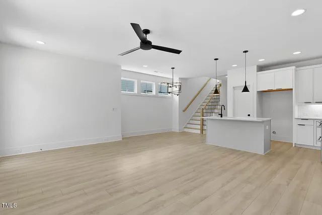 a view of an empty room with kitchen and window