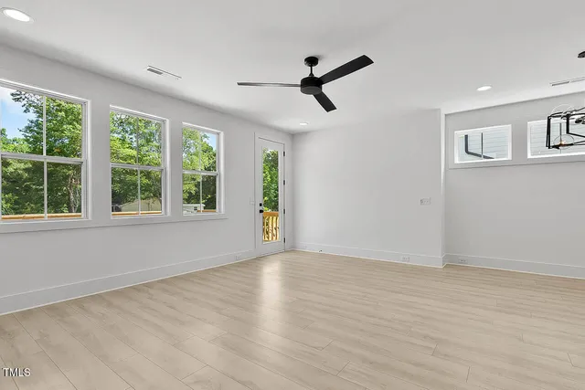 a view of an empty room with a window and wooden floor