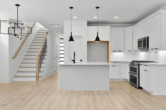 a kitchen with stainless steel appliances granite countertop a refrigerator a stove and a wooden floors