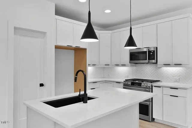 a kitchen with stainless steel appliances a sink a microwave a stove and a refrigerator with wooden floor