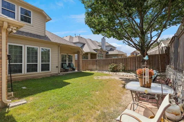 a backyard of a house with table and chairs and potted plants