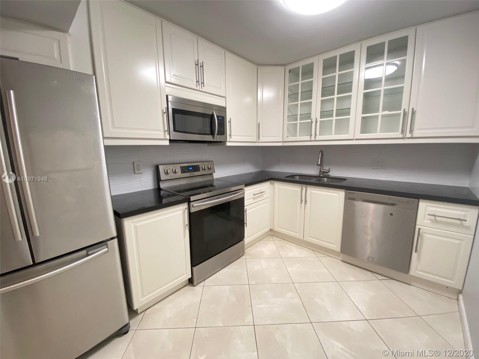 a kitchen with granite countertop a refrigerator sink and microwave