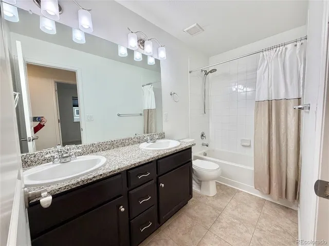 a bathroom with a granite countertop sink toilet a large mirror a shower and a bathtub