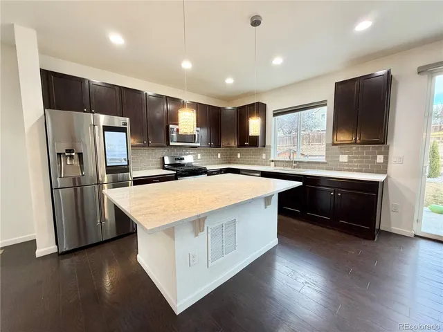a kitchen with stainless steel appliances a sink a stove a refrigerator and a center island