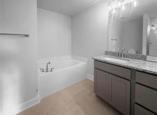 a bathroom with a granite countertop sink and a bathtub