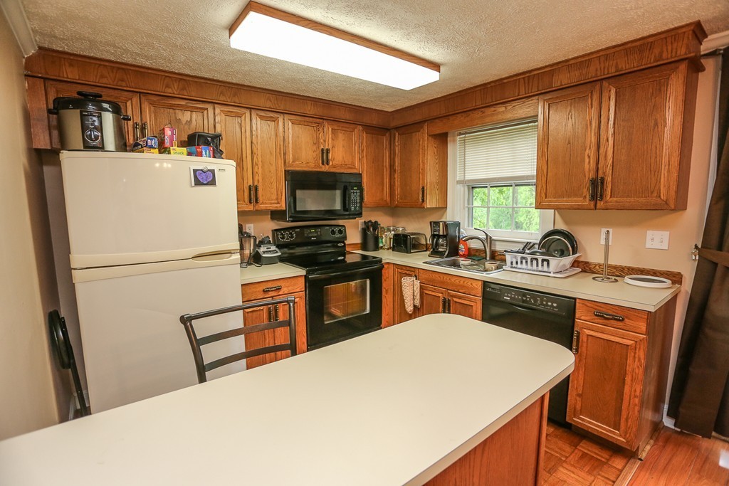 241 Winding Pond Road, Unit 241 Londonderry, NH 03053 - Photo 5 of 30 a kitchen with stainless steel appliances a refrigerator sink stove microwave and cabinets