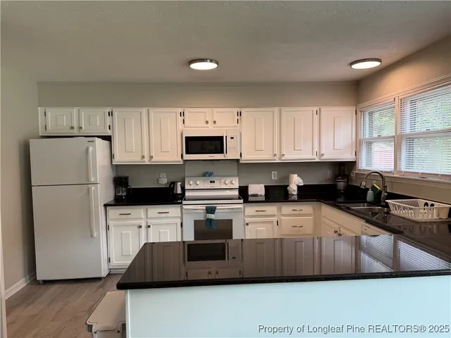 a kitchen with a sink a microwave a refrigerator and cabinets