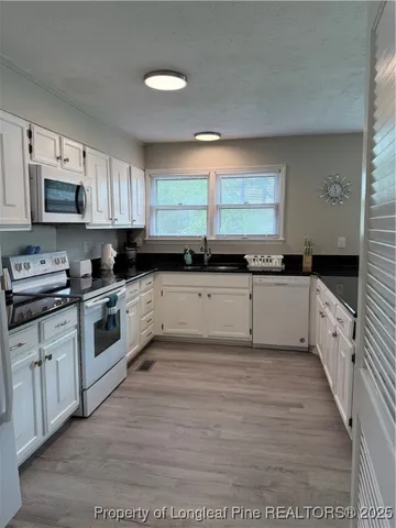 a large kitchen with granite countertop a stove top oven a sink a counter space and cabinets