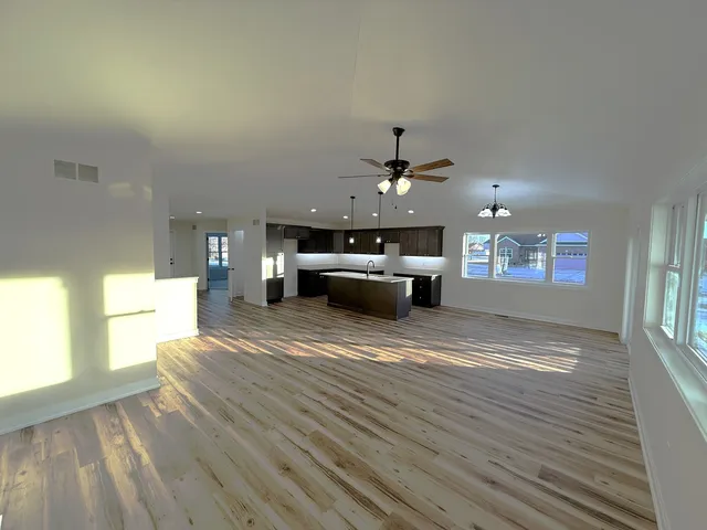 a large kitchen with stainless steel appliances granite countertop a sink dishwasher a stove and a dining table with wooden floor