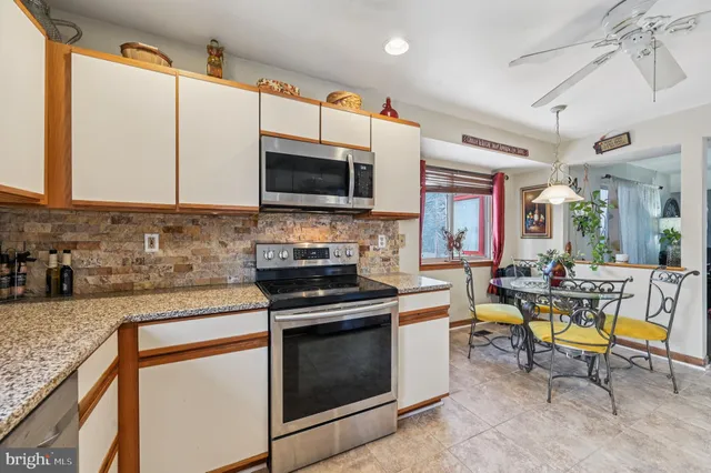 a kitchen with granite countertop stainless steel appliances a sink stove top oven and cabinets