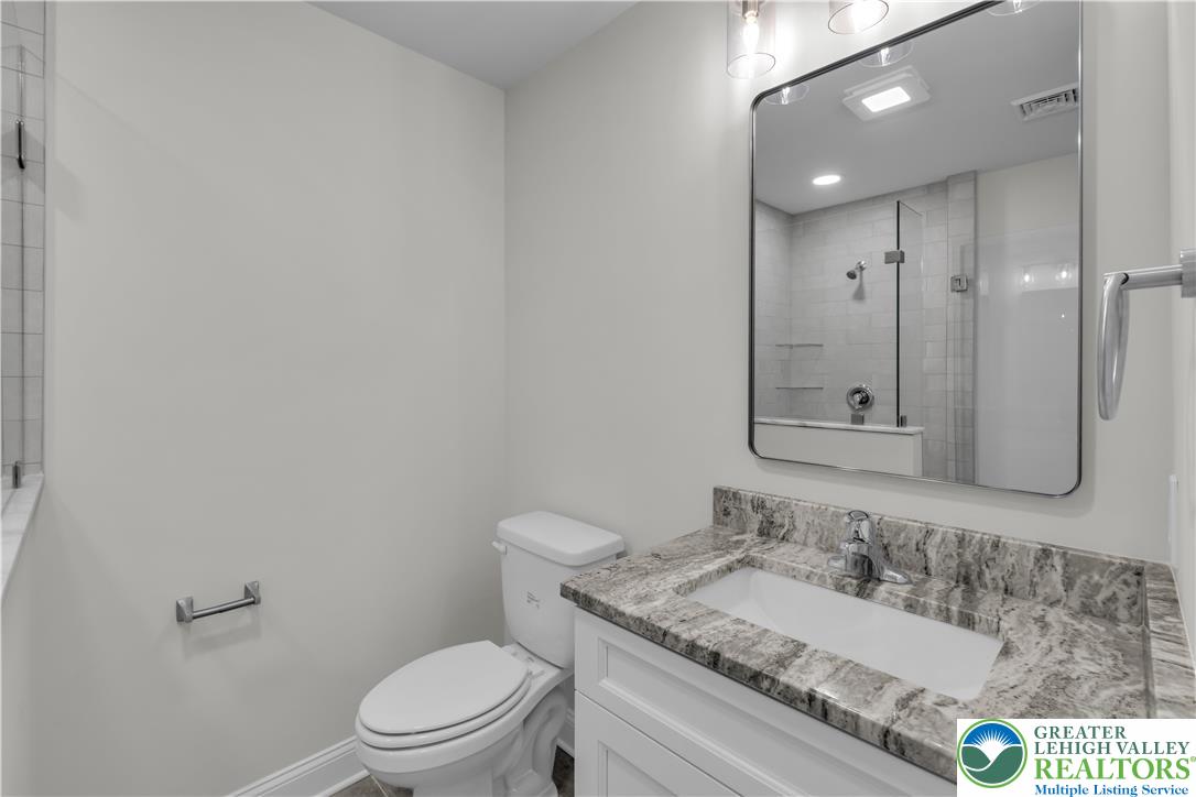 1480 Bushkill Center Road Nazareth, PA 18064 - Photo 36 of 55 a bathroom with a granite countertop sink a toilet and a mirror