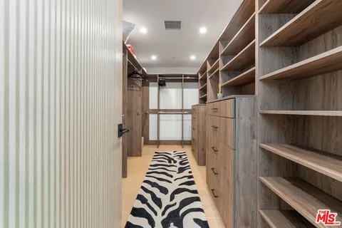 a view of walk in closet with wooden floor and windows