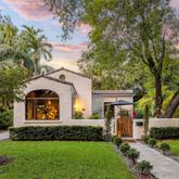 a front view of a house with a garden and trees