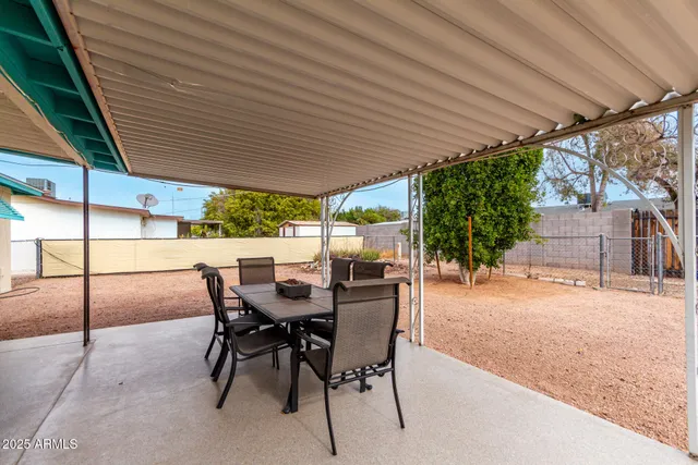 a view of a patio with table and chairs and a barbeque