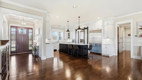 a large white kitchen with cabinets a sink a window and stainless steel appliances