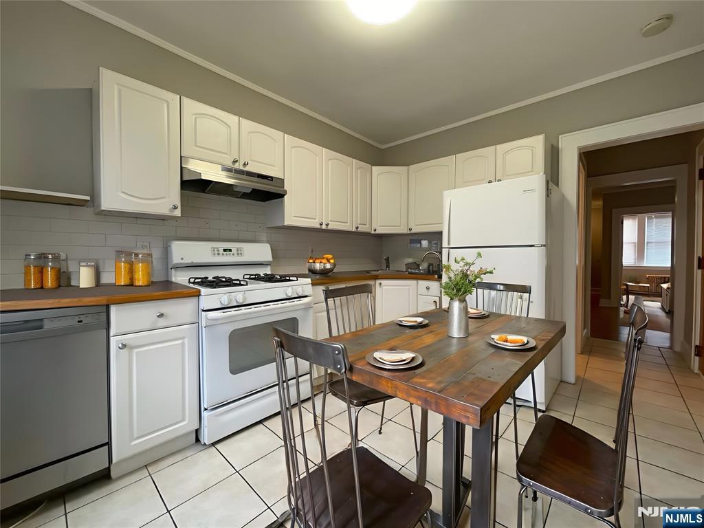 283-285 Maple Street, Unit L1 Kearny, NJ 07032 - Photo 3 of 8 a kitchen with stainless steel appliances granite countertop a table chairs and white cabinets