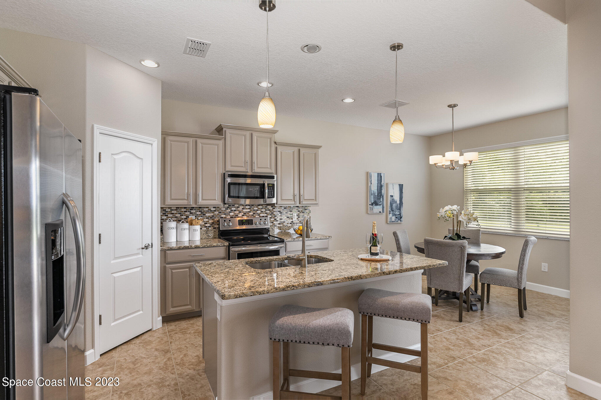 3545 Sansome Circle Melbourne, FL 32940 - Photo 8 of 27 a kitchen with kitchen island granite countertop a refrigerator a stove a sink and chairs
