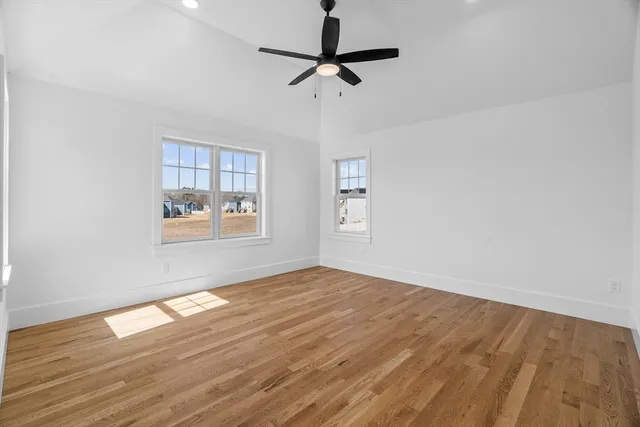 a view of empty room with wooden floor and fan