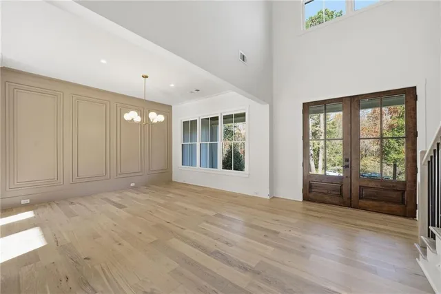 a view of an empty room with wooden floor staircase and a kitchen view