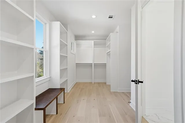 a large white kitchen with stainless steel appliances kitchen island granite countertop a large cabinets a sink and a counter top space