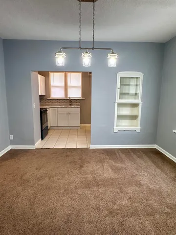 an empty room with chandelier fan and windows