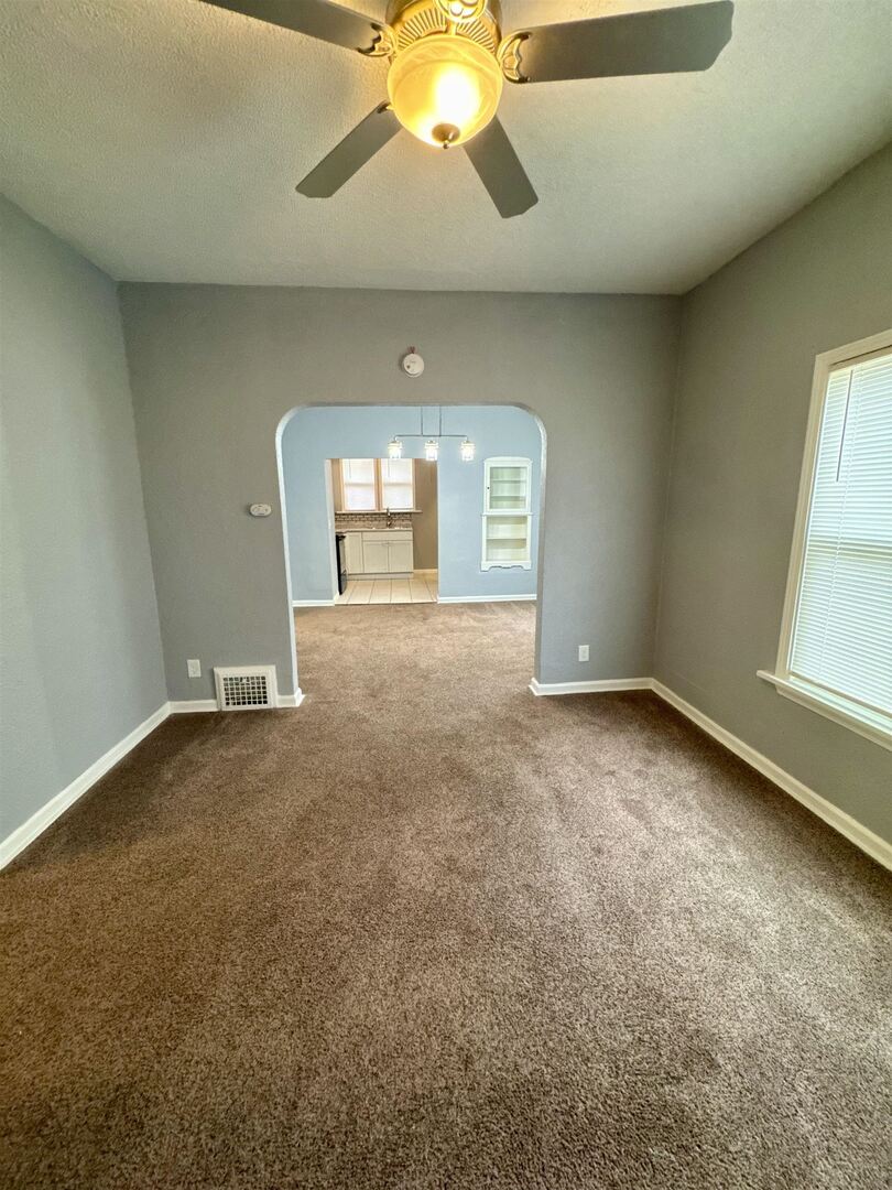 4227 11th Street Rock Island, IL 61201 - Photo 4 of 12 an empty room with a chandelier fan and windows
