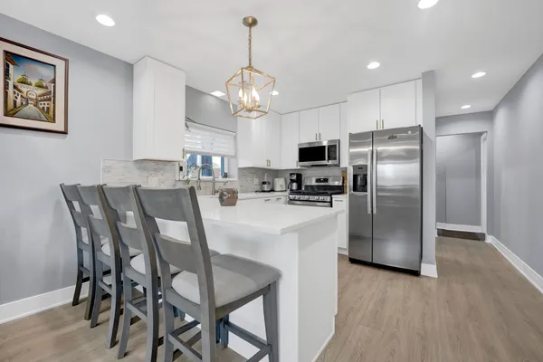 a kitchen with stainless steel appliances a dining table chairs refrigerator and microwave