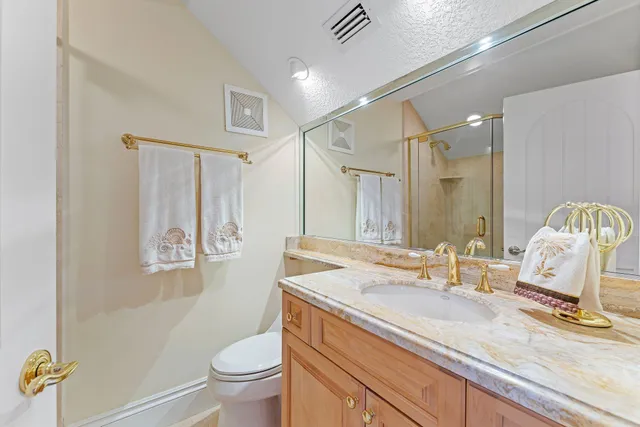 a bathroom with a granite countertop sink mirror vanity and toilet