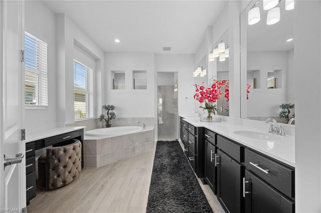 5415 Ternberry Road Ave Maria, FL 34142 - Photo 21 of 45 a spacious bathroom with a double vanity sink a large mirror and a bathtub