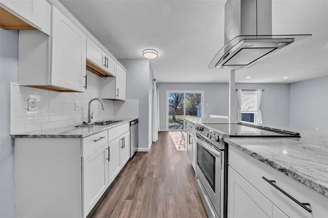 a large kitchen with granite countertop a sink and cabinets