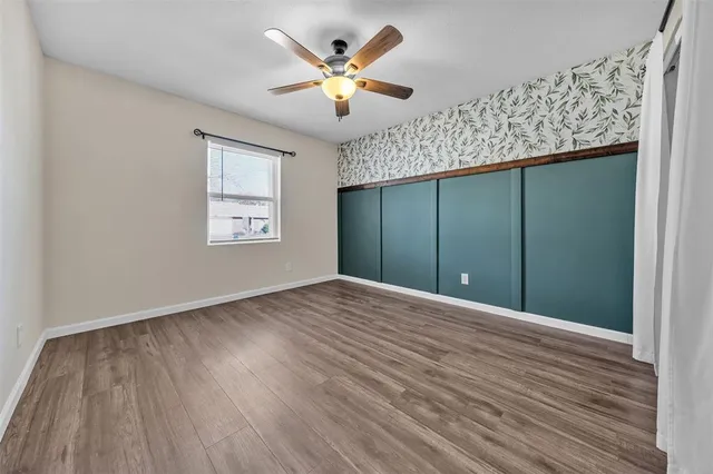 a view of an empty room with a window and wooden floor