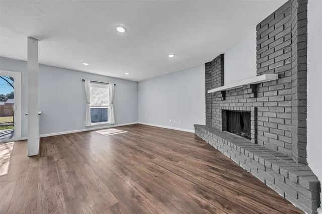 an empty room with wooden floor a fireplace and windows