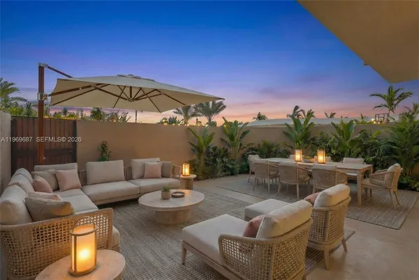 a view of a patio with couches table and chairs under an umbrella with a fire pit