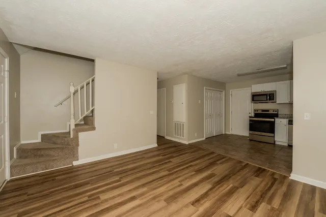 a view of kitchen and empty room with wooden floor