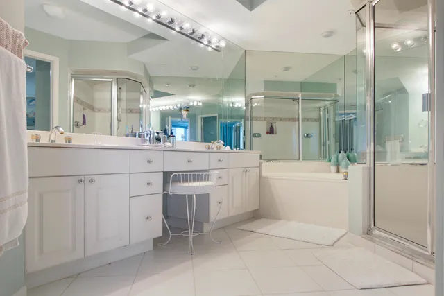 a spacious bathroom with a granite countertop sink a mirror and a bathtub