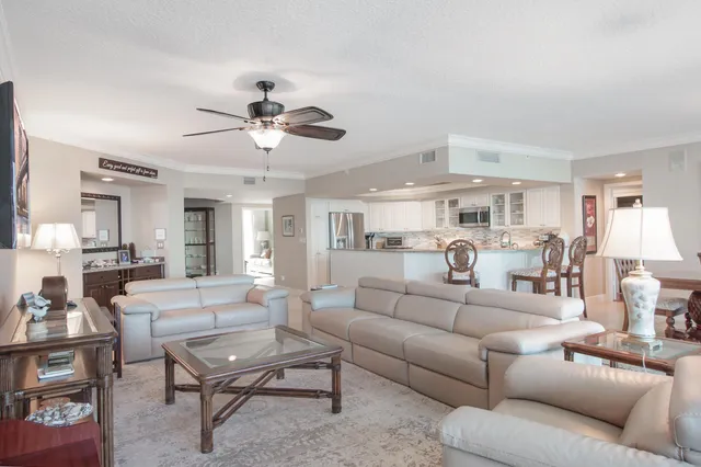 a living room with furniture kitchen view and a chandelier