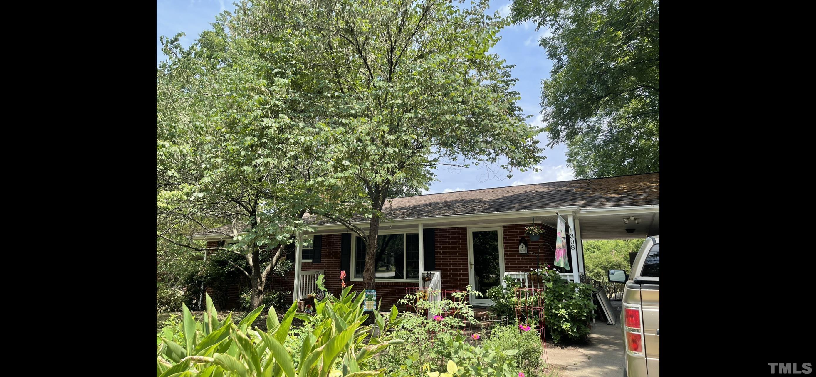 308 Parham Road Henderson, NC 27536 - Photo 21 of 27 a view of a house with potted plants and a large tree