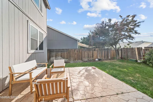 a view of backyard with table and chairs and wooden fence