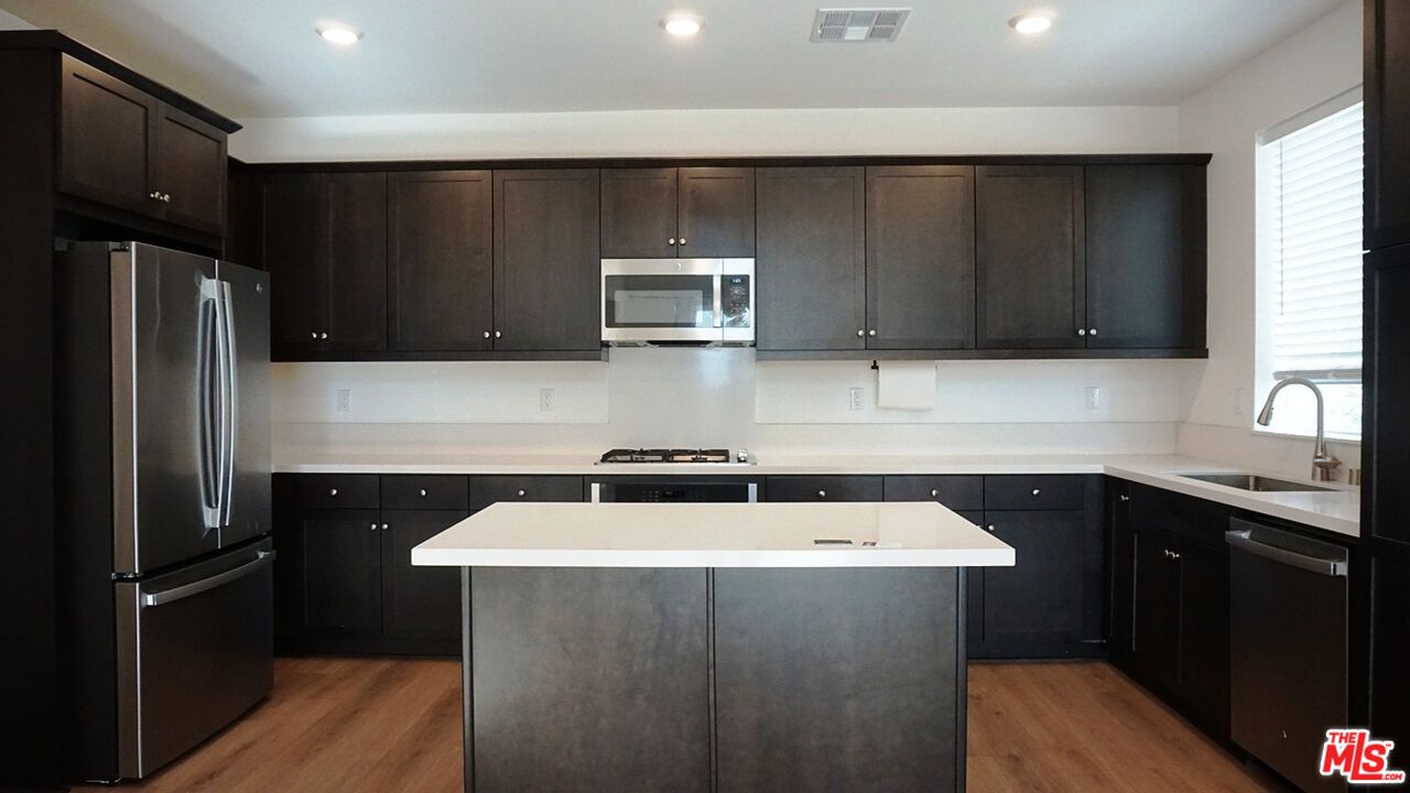 8564 Exposition Street Chino, CA 91708 - Photo 10 of 29 a kitchen with a sink a refrigerator and cabinets