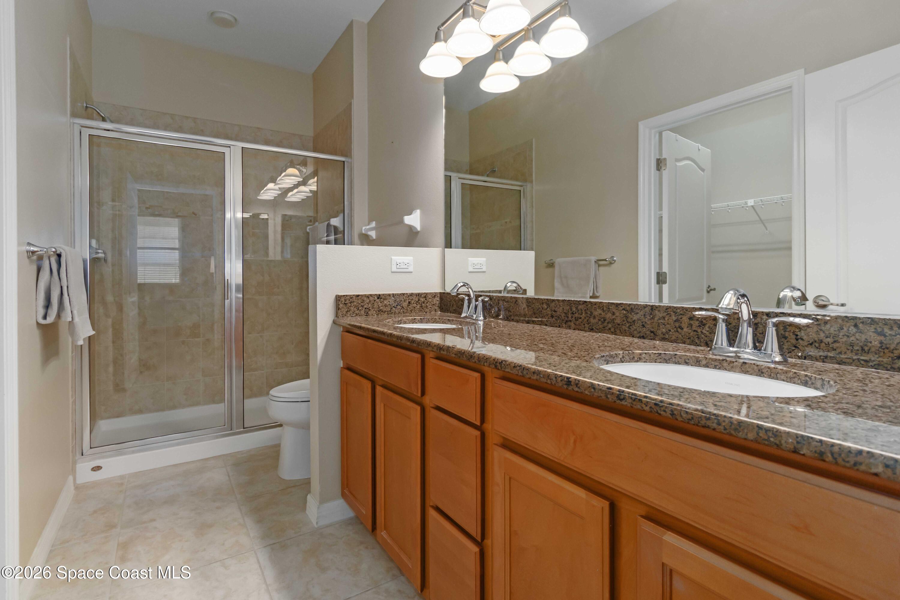 6604 Pico Street Melbourne, FL 32940 - Photo 16 of 36 a bathroom with a granite countertop sink a toilet a mirror and shower