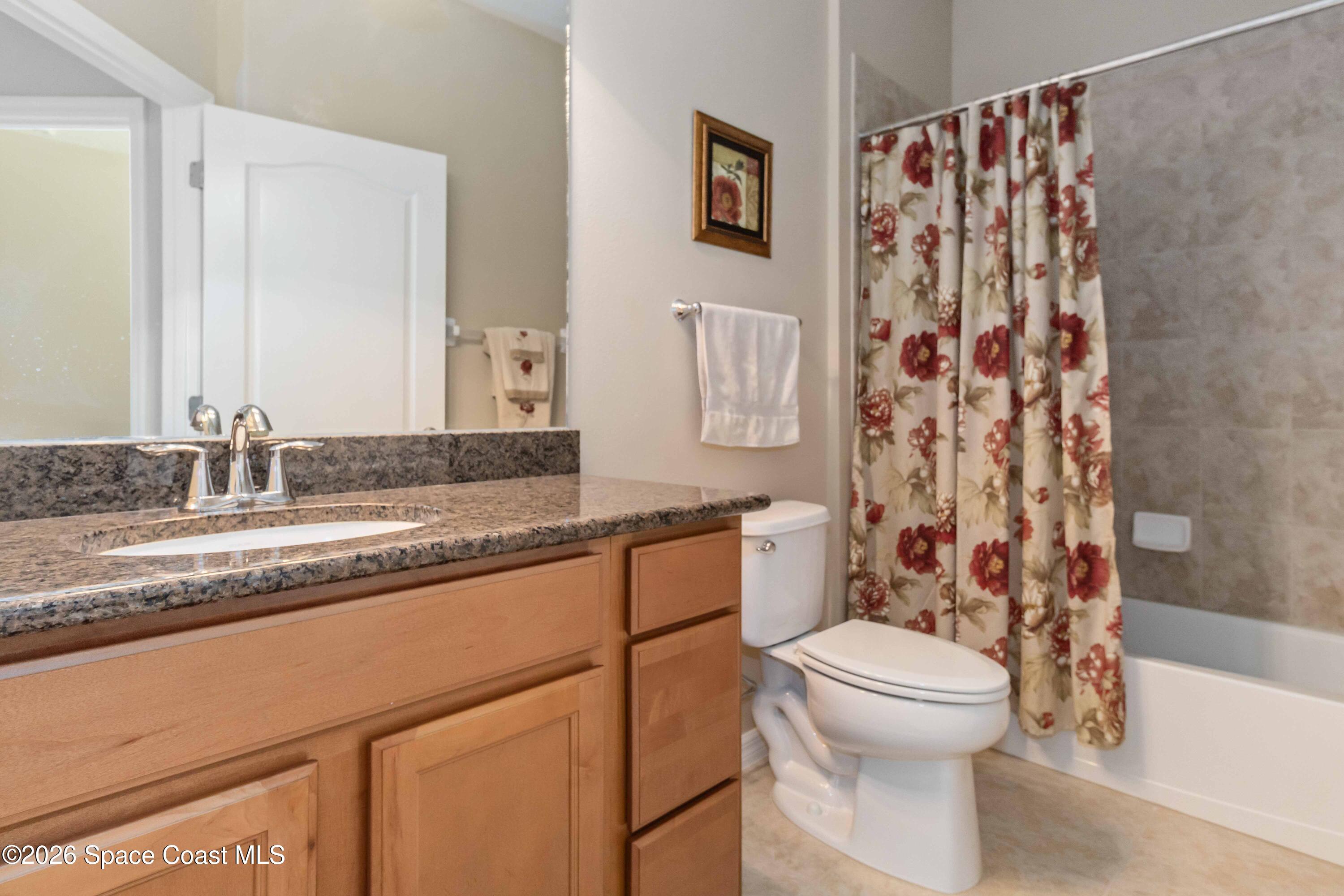 6604 Pico Street Melbourne, FL 32940 - Photo 18 of 36 a bathroom with a granite countertop sink toilet and shower