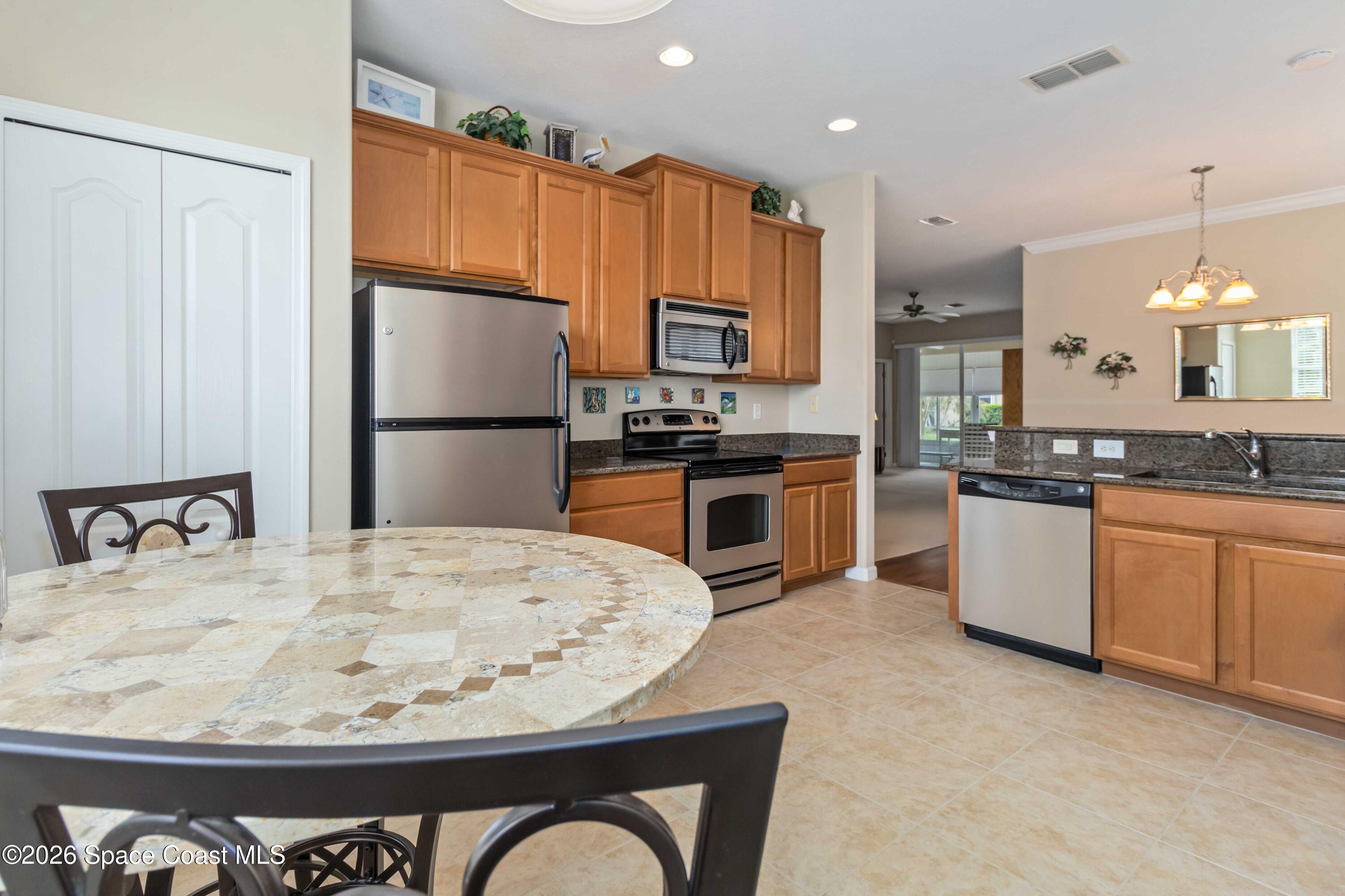 6604 Pico Street Melbourne, FL 32940 - Photo 10 of 36 a kitchen with stainless steel appliances kitchen island granite countertop a refrigerator a stove a sink a oven with a dining table and chairs