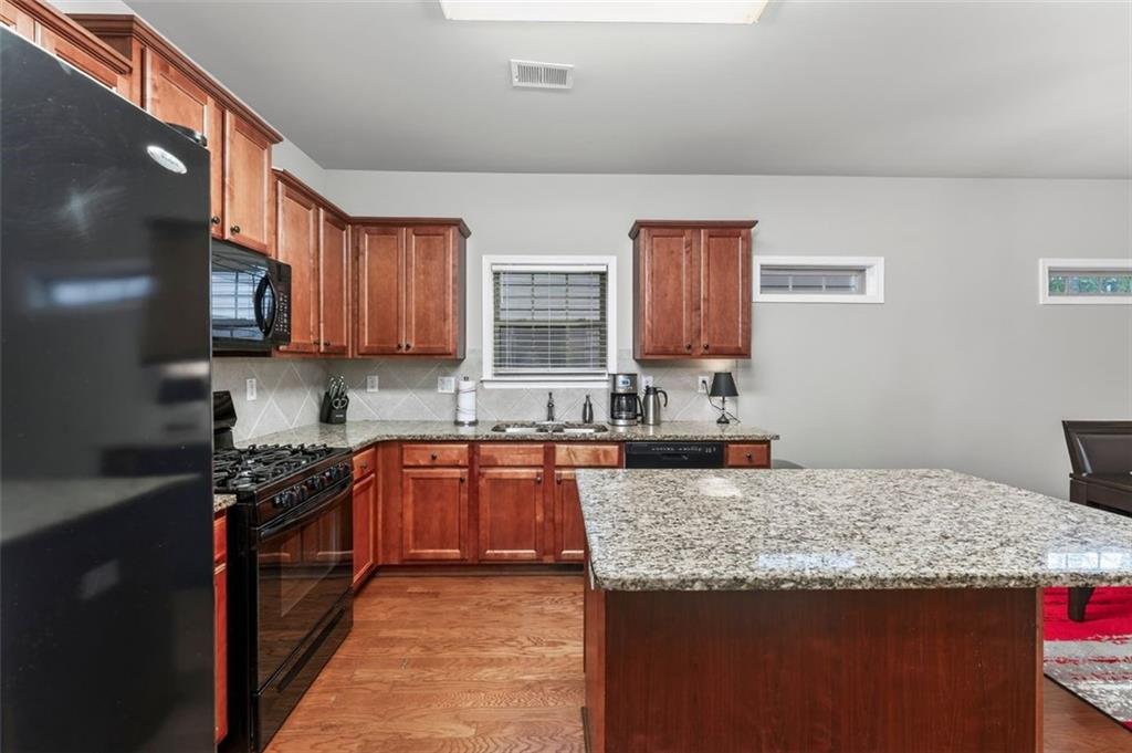 113 Tyson Woods Road Acworth, GA 30102 - Photo 16 of 37 a kitchen with granite countertop a stove top oven a sink dishwasher and cabinets with wooden floor