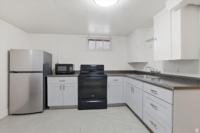744 North 500 East Logan, UT 84321 - Photo 21 of 29 Basement Kitchen with black appliances, dark countertops, white cabinetry, and a textured ceiling
