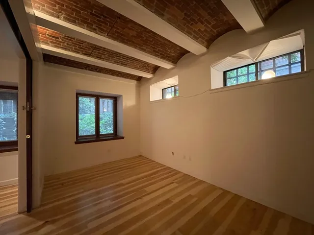 a view of a hallway with wooden floor and a window